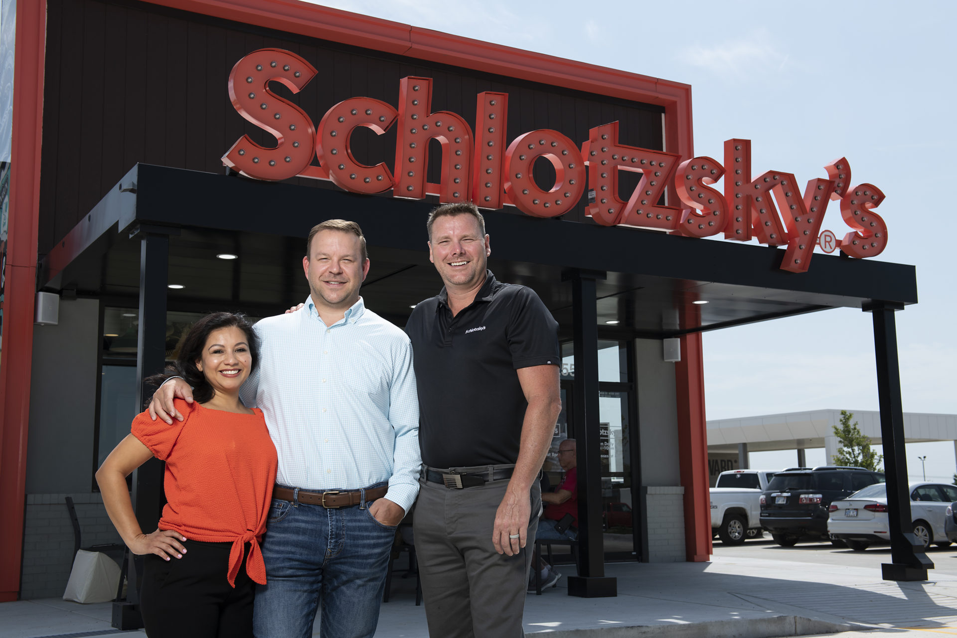 Three people standing in front of a Schlotzsky's establishment