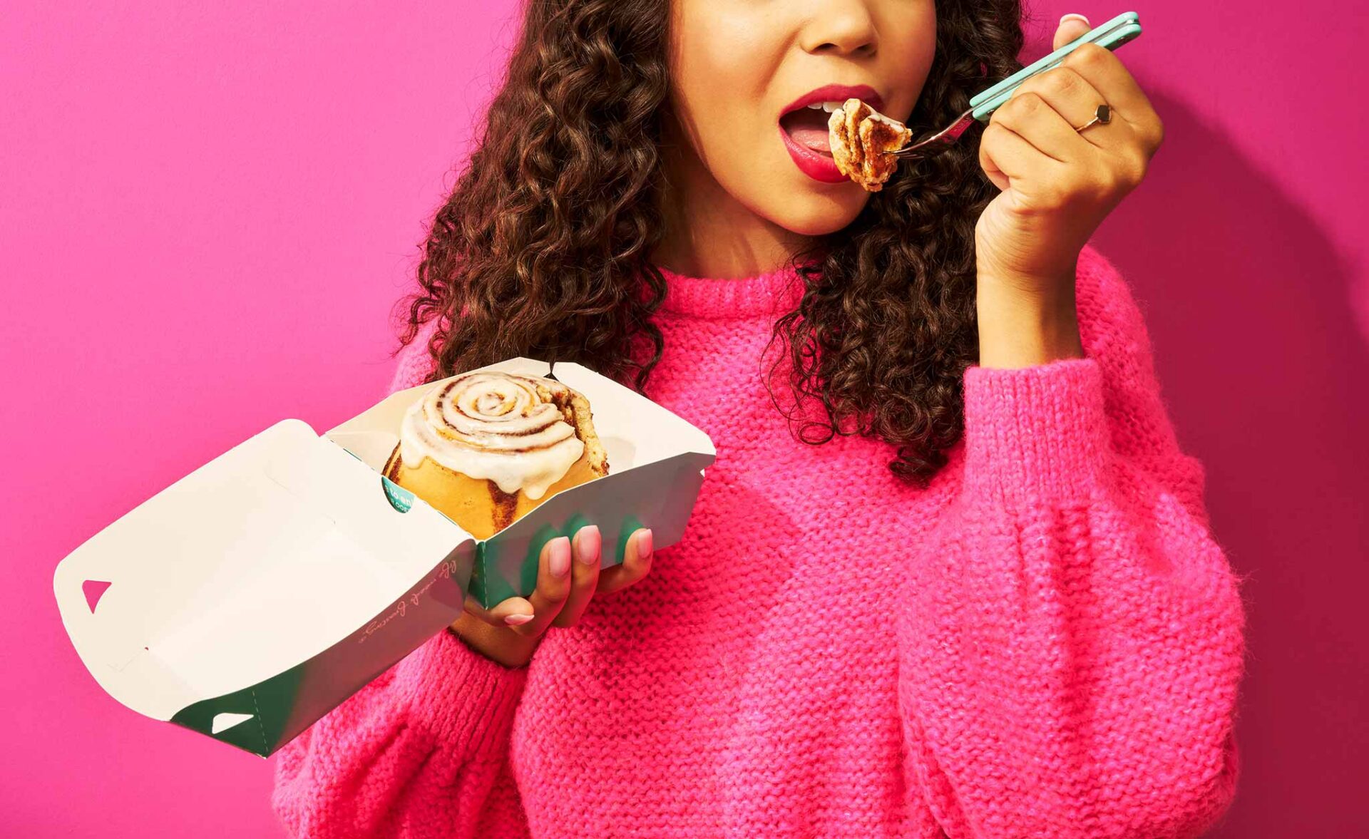 A Woman Eating Food From Cinnabon